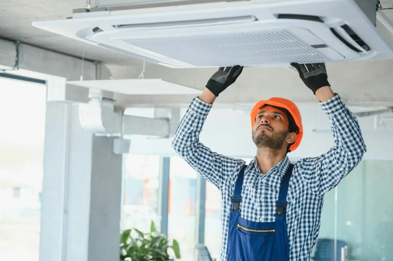 HVAC service technician performing air conditioner repair in a home